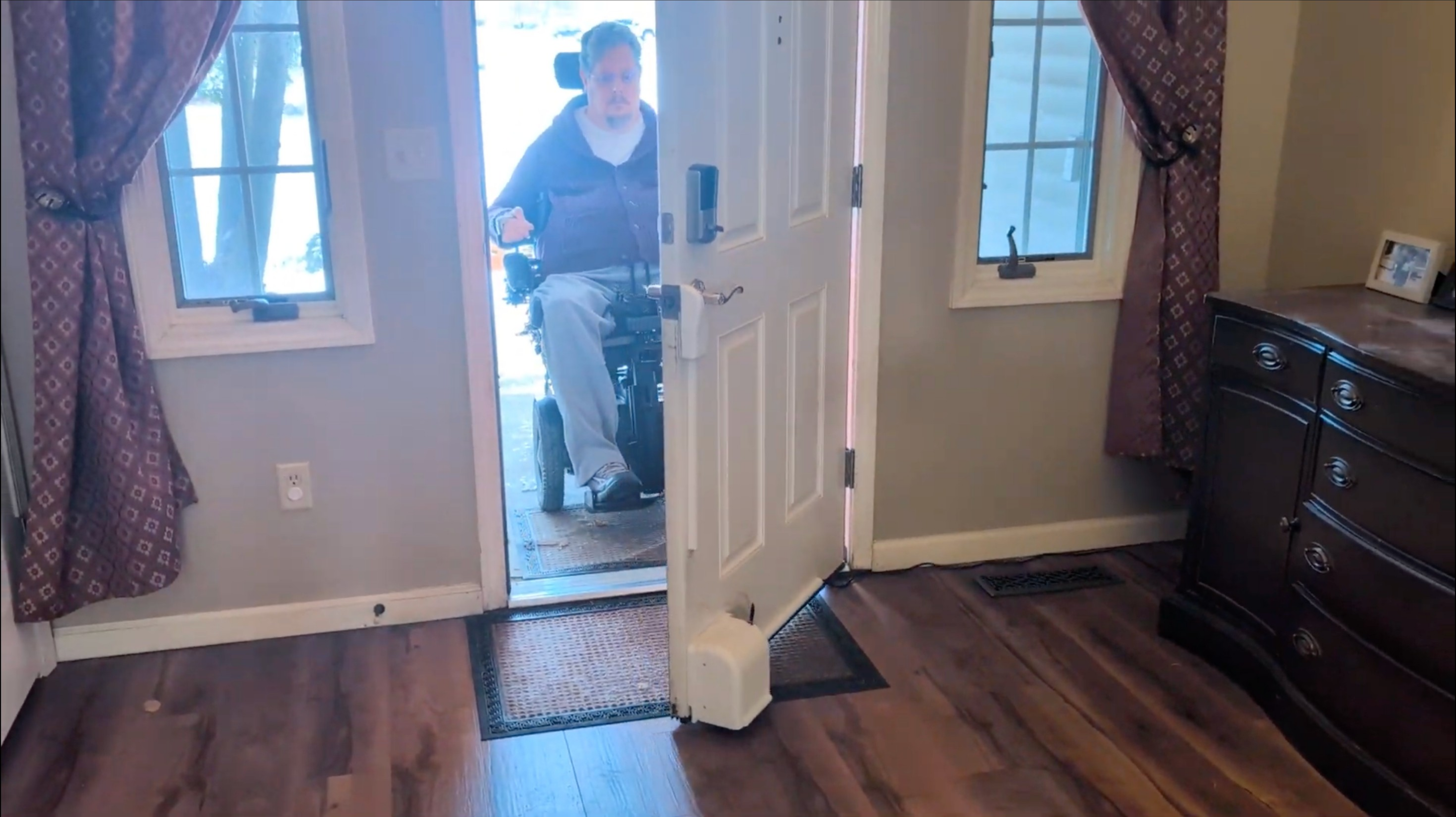 Man in powered wheelchair entering through a door with Theodoor